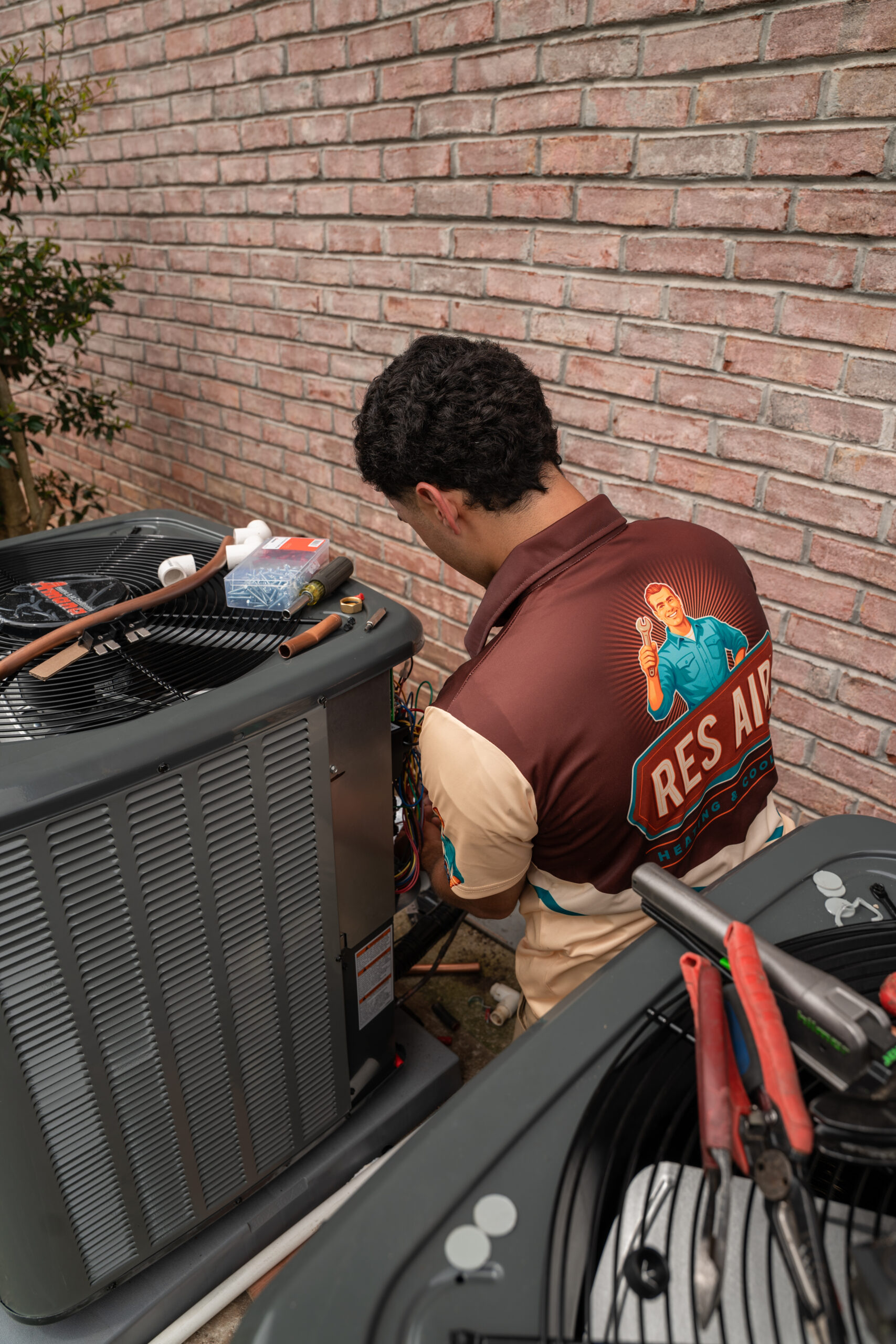 HVAC technician performing emergency air conditioning repair on a malfunctioning AC unit